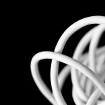 Zwinięty biały kabel ułożony w pętle na czarnym tle.