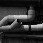 Kilka białych plastikowych rur kanalizacyjnych zamontowanych i połączonych na ścianie budynku