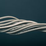 Kilka białych przewodów elektrycznych skręconych razem na ciemnym tle